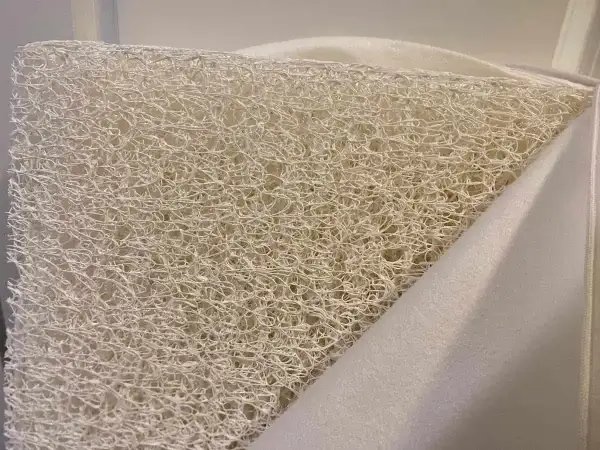Close-up of a white, airy, woven material, revealing what the Newton mattress is made of: a breathable, open-cell core.