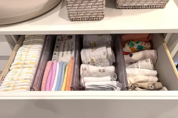 Drawer neatly organized with diapers, wipes, colorful washcloths, and folded baby clothes. A perfect example of how to organize baby stuff efficiently.