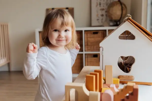 A happy toddler plays with wooden blocks, a perfect scene for learning for 1 year olds.