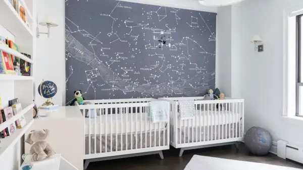 Two white cribs in a nursery with a constellation mural. This is a perfect example of baby boys nursery designs, inspiring dreams of the stars.