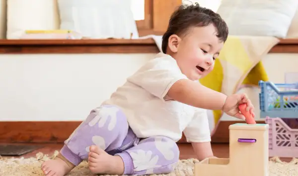 A baby's hand carefully places a toy, showcasing developing baby hand eye coordination.