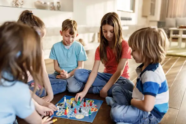 Five children enjoy a board game together, a perfect example of fun things to do with siblings.