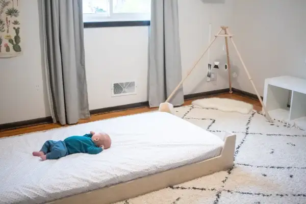 Newborn baby sleeps peacefully on a floor bed.