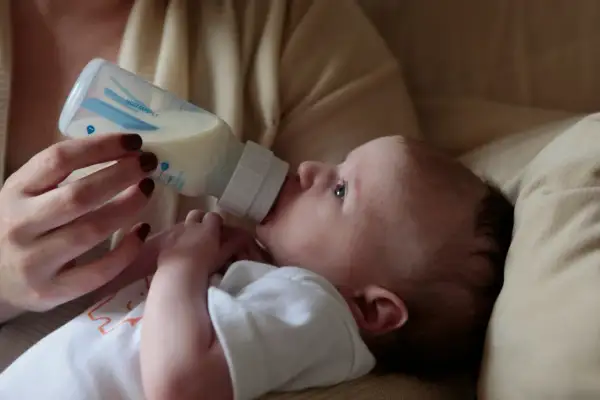A baby drinks from a bottle. Concerns exist about does bottle feeding affect teeth alignment, but this image focuses on a moment of nourishment.