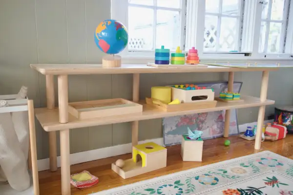 A Montessori shelf for a 1-year-old features a globe, stacking toys, and wooden puzzles, encouraging exploration and learning.