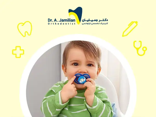 A baby with a pacifier, or binky, in their mouth. The pacifier has a blue elephant design.