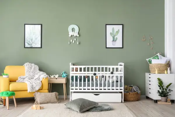 A serene nursery with a yellow armchair, white crib, and cactus art. A perfect nursery painting idea for a calm and natural space.