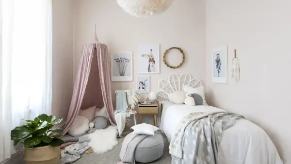 A dreamy baby girls bedroom with a pink canopy, cloud-patterned blanket, and whimsical art.