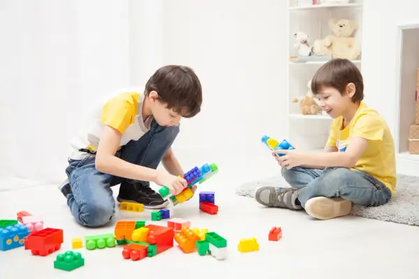 Two boys happily build with colorful blocks, showing great ideas for what to play indoors.