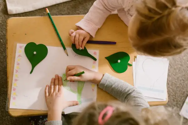 Children engage in Montessori fine motor activities, drawing and manipulating leaf shapes on a wooden table.